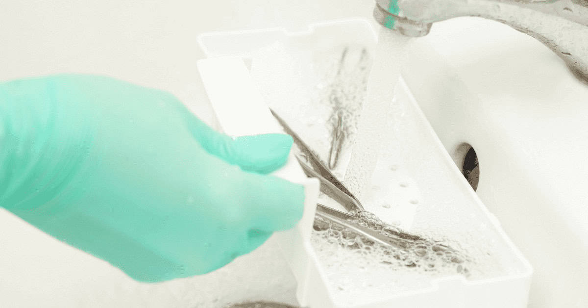 Dissection of eyelashes with tweezers, lash extension removal, beauty and makeup tools for eye enhancement, close-up of eye makeup removal process.