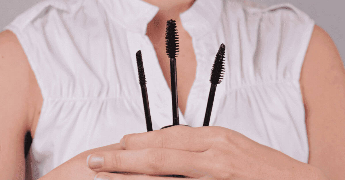 Voluminous mascara wands held in hand, close-up of eye makeup essentials, perfect for enhancing eyelashes, dappered chic beauty blog image.
