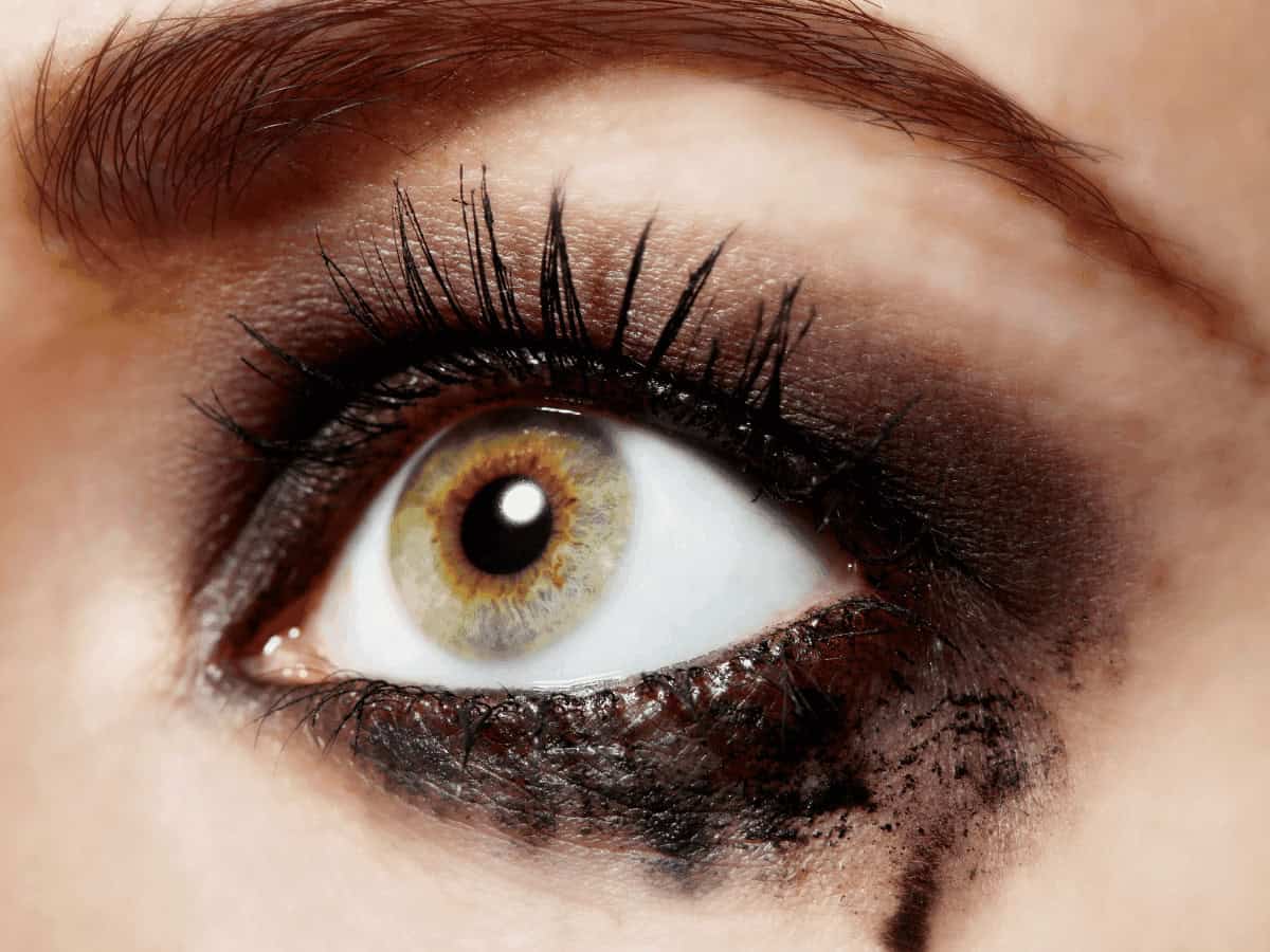 Vivid close-up of a woman's eye showcasing dramatic smoky eye makeup, long voluminous eyelashes, and detailed iris with golden hues.